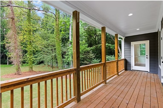 Covered rear porch with stained wood posts and railing overlooking wooded acreage at the Stone Mountain home