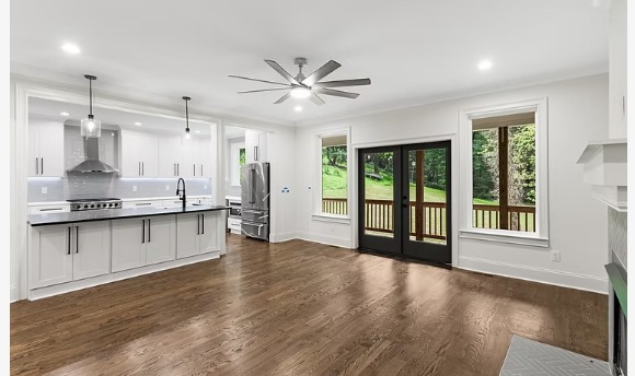 Open great room and kitchen of the Stone Mountain home with white cabinetry, hardwood floors and rear French doors